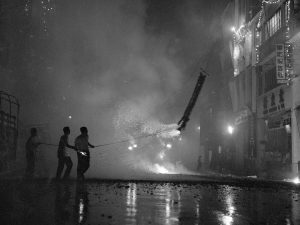Time and Tide by Foo Tee Jun - Setting off firecrackers along Hong Kong Street, c. 1960s