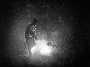 Time and Tide by Foo Tee Jun - Man ignites firecrackers on Hong Kong Street, c. 1960s