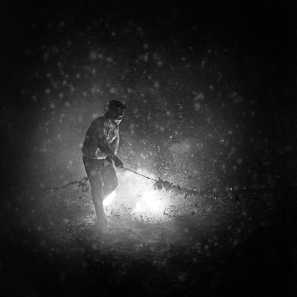 Time and Tide by Foo Tee Jun - Man ignites firecrackers on Hong Kong Street, c. 1960s