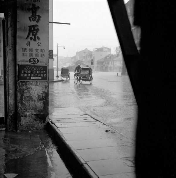 Time and Tide by Foo Tee Jun - Scene of rainy day along Chulia Street, c. 1960s