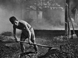 Passing Time by Lui Hock Seng - Man shovelling crushed cockle shells to make whitewash paint, Tanah Merah, c. 1960s – 1970s